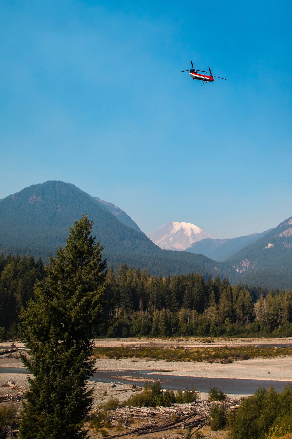 Helicopters soar over the Cowlitz River in front of Mount Rainier while responding to the Goat Rocks Fire on Sunday.