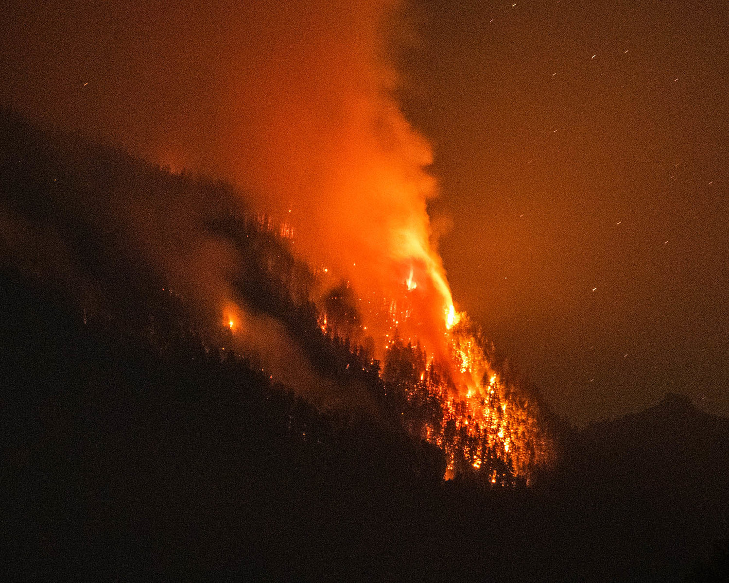 Flames from the Goat Rocks Fire ignites trees Sunday night as seen from Cannon Road in Packwood over Butler Creek.