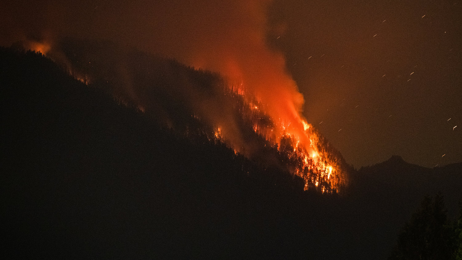 Flames from the Goat Rocks Fire ignites trees Sunday night as seen from Cannon Road in Packwood over Butler Creek.