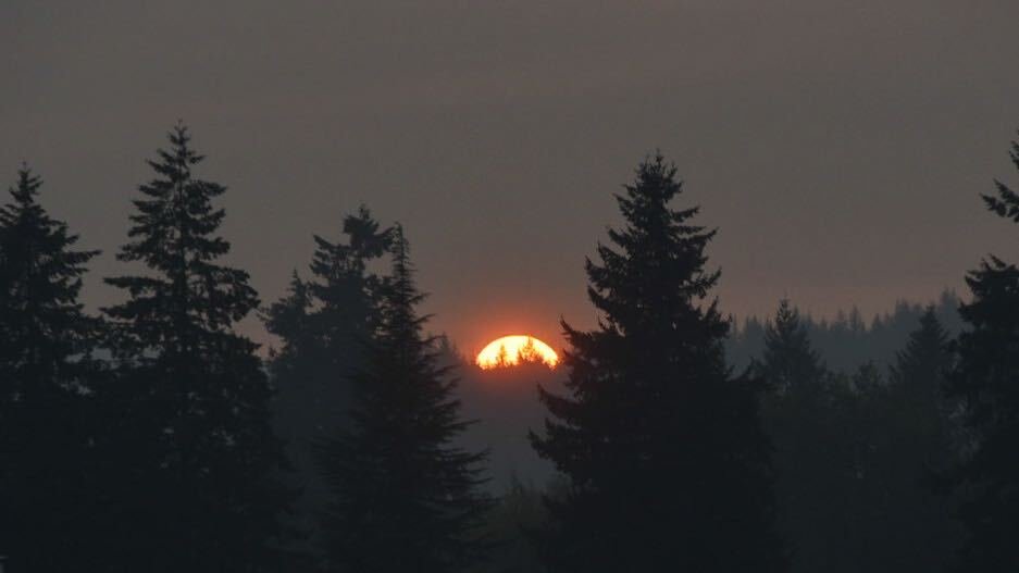 The sun glows orange through wildfire smoke as it sets behind the Chehalis-Centralia airport on Wednesday evening.