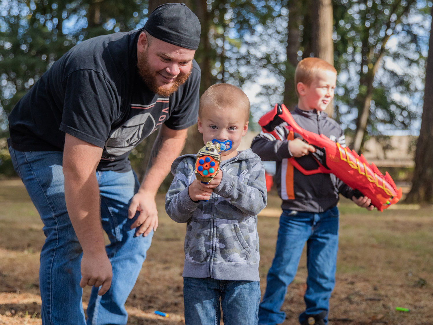 Andy Sickles smiles as Luke, 2, aims his six-shooter alongside his brother Abram, 6, during a Nerf War Sunday afternoon at Borst Park.