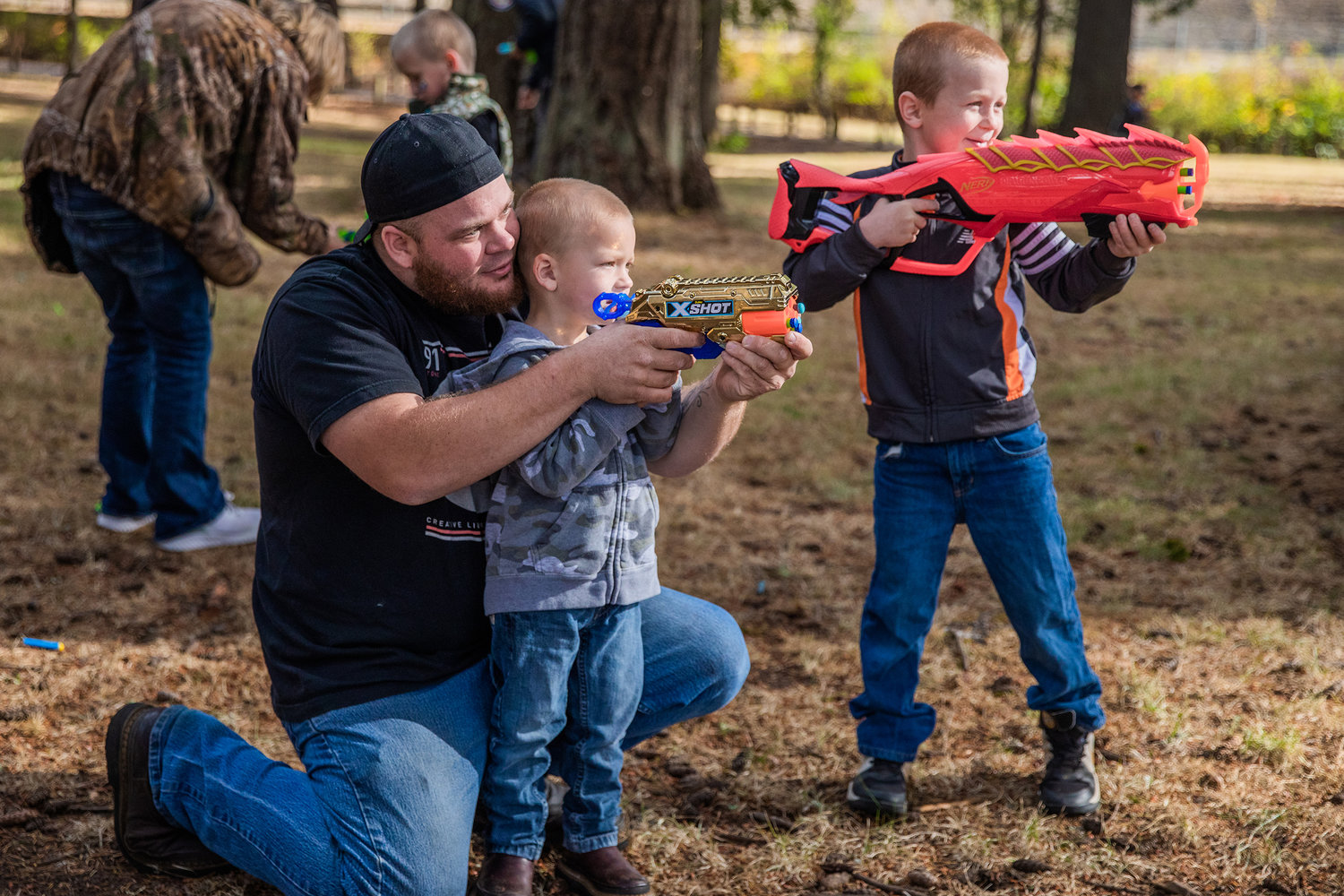 Andy Sickles helps as Luke, 2, aims his six-shooter alongside his brother Abram, 6, during a Nerf War Sunday afternoon at Borst Park in Centralia.