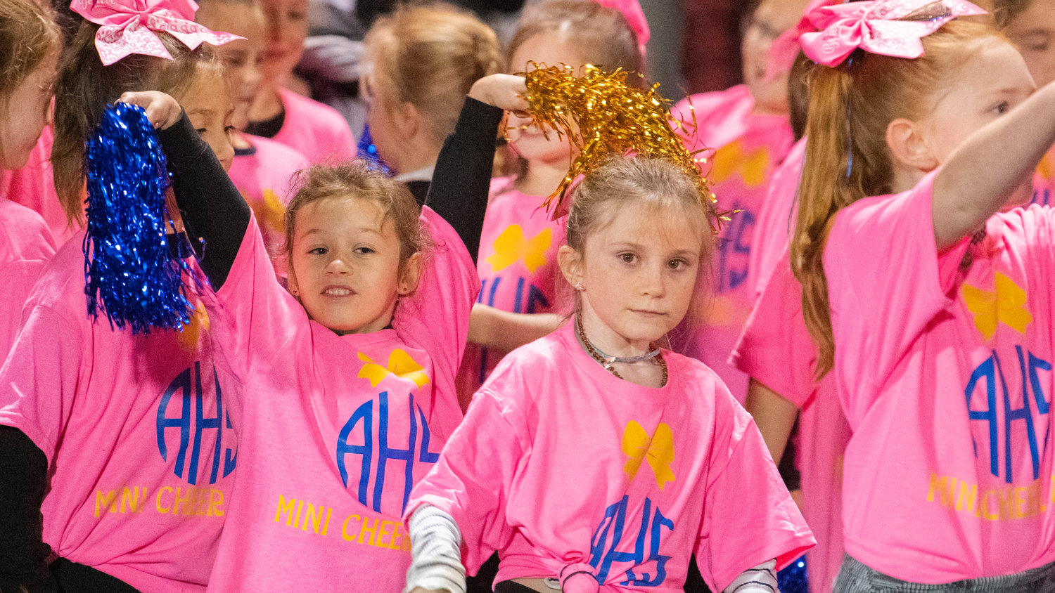 Mini cheerleaders look on and wave their pom-poms as they prepare to take the field at halftime during a Thursday night game at Pirate Stadium.