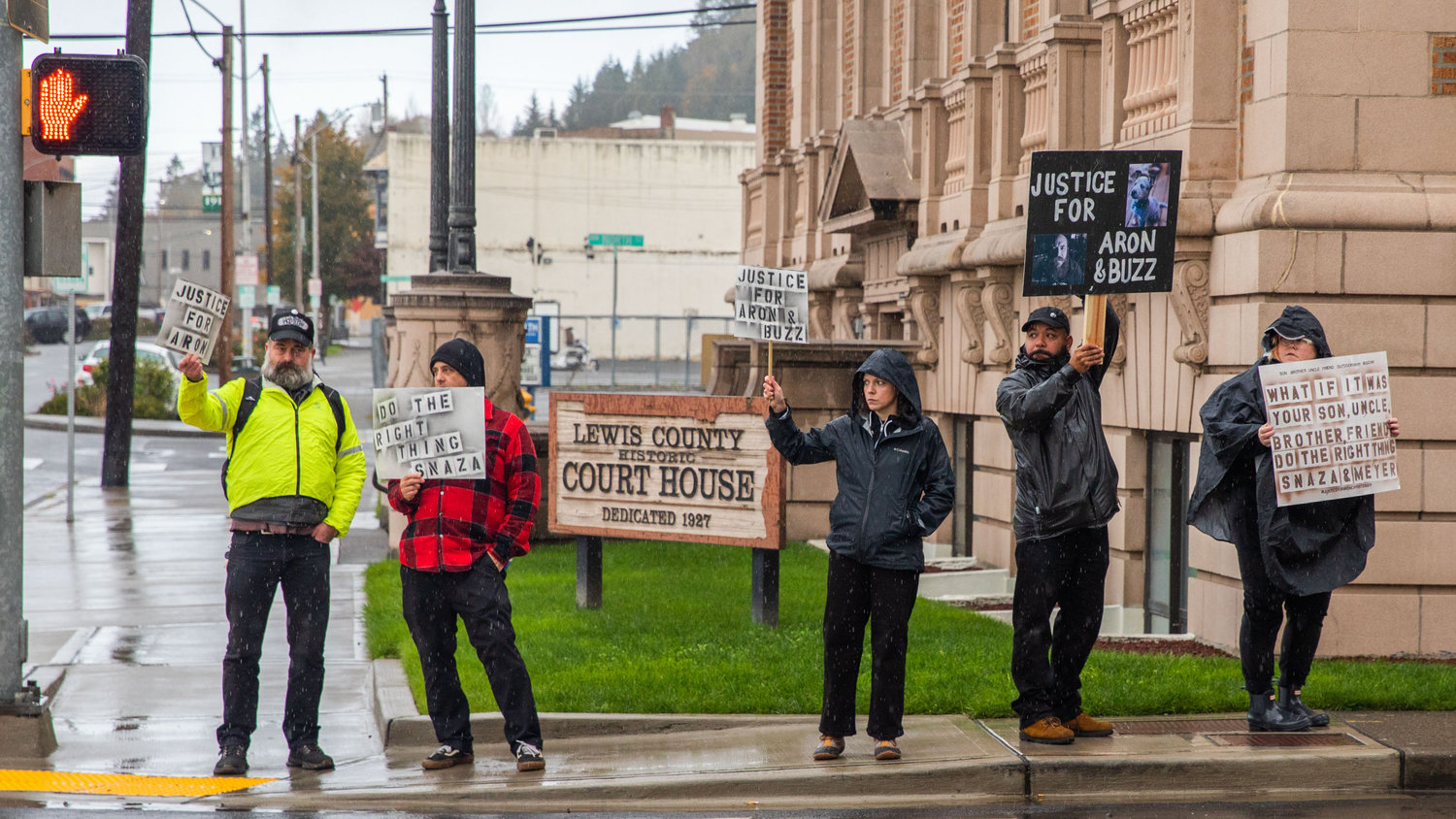 Demonstrators stand in the rain outside the Lewis County Law and Justice Center in Chehalis on Saturday while demanding justice for Aron Christensen and his dog Buzz.