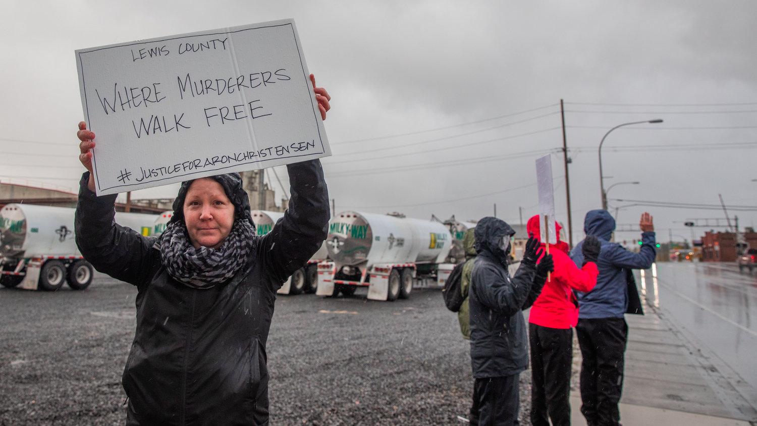 Demonstrators stand in the rain outside the Lewis County Law and Justice Center in Chehalis on Saturday while demanding justice for Aron Christensen.