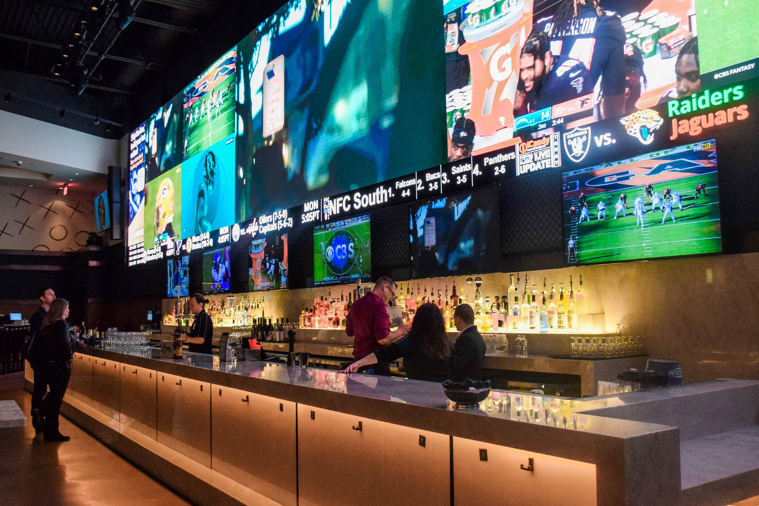 Bartenders at The Stadium Bar & Grill make drinks in front of the restaurant’s video wall during the grand opening event for sports betting on Nov. 6.