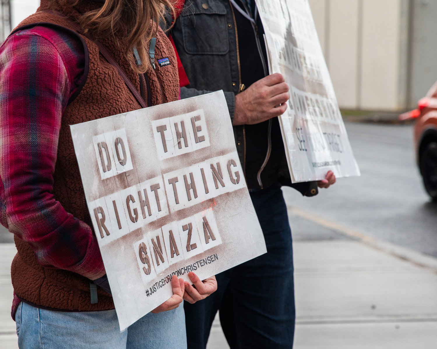 Demonstrators hold signs while demanding justice for Aron Christensen and his dog Buzz in Chehalis on Saturday.