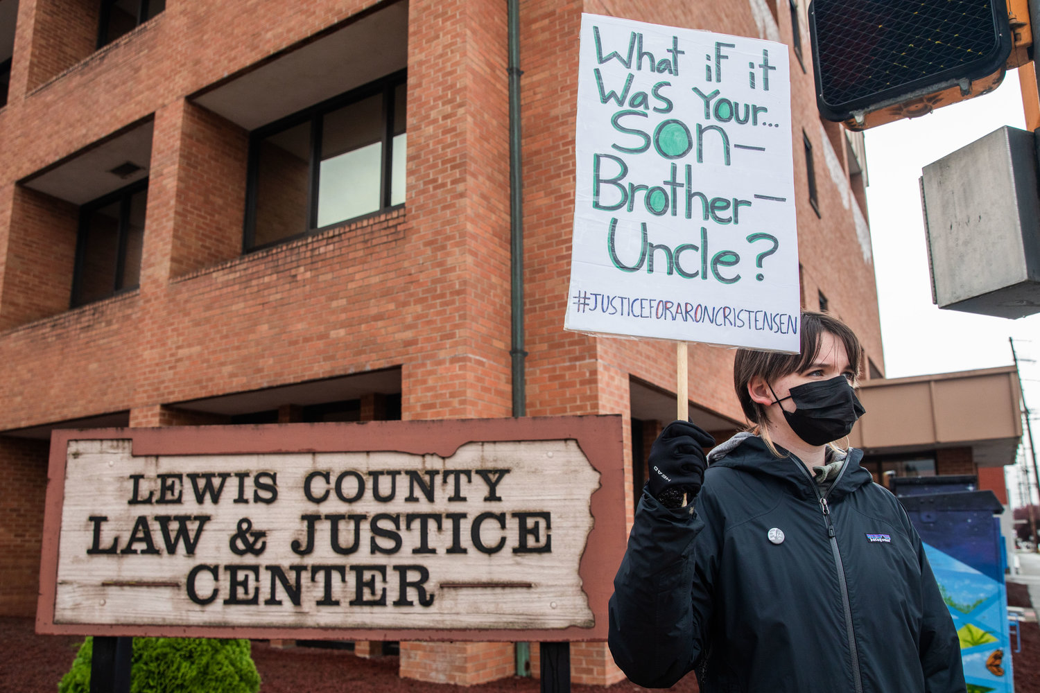 Demonstrators hold signs outside the Lewis County Law and Justice Center while demanding justice for Aron Christensen and his dog Buzz in Chehalis on Saturday.
