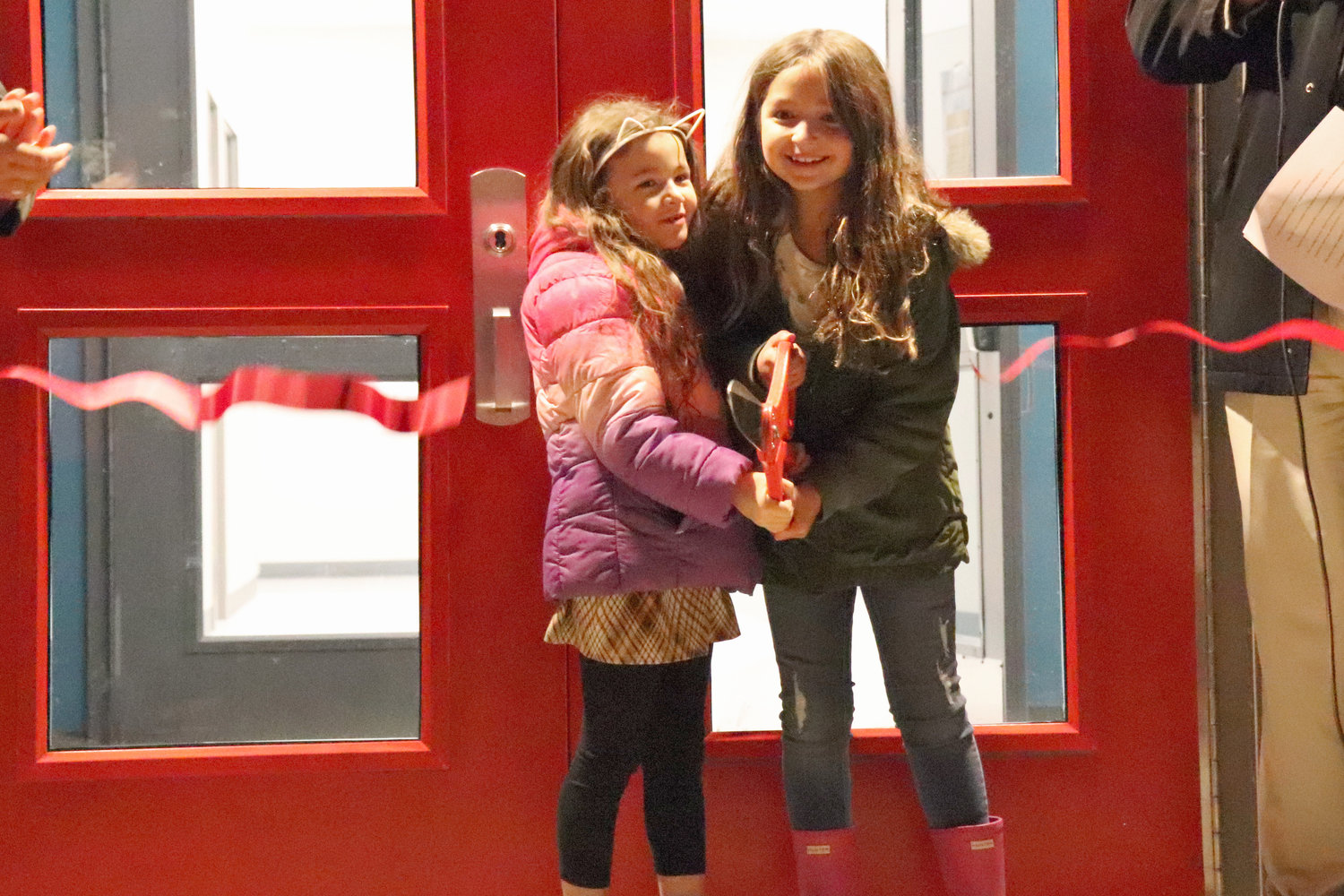 Seven-year-olds Lexie and Claire cut a red ribbon during a dedication ceremony to the new Oakville Elementary School on Wednesday.