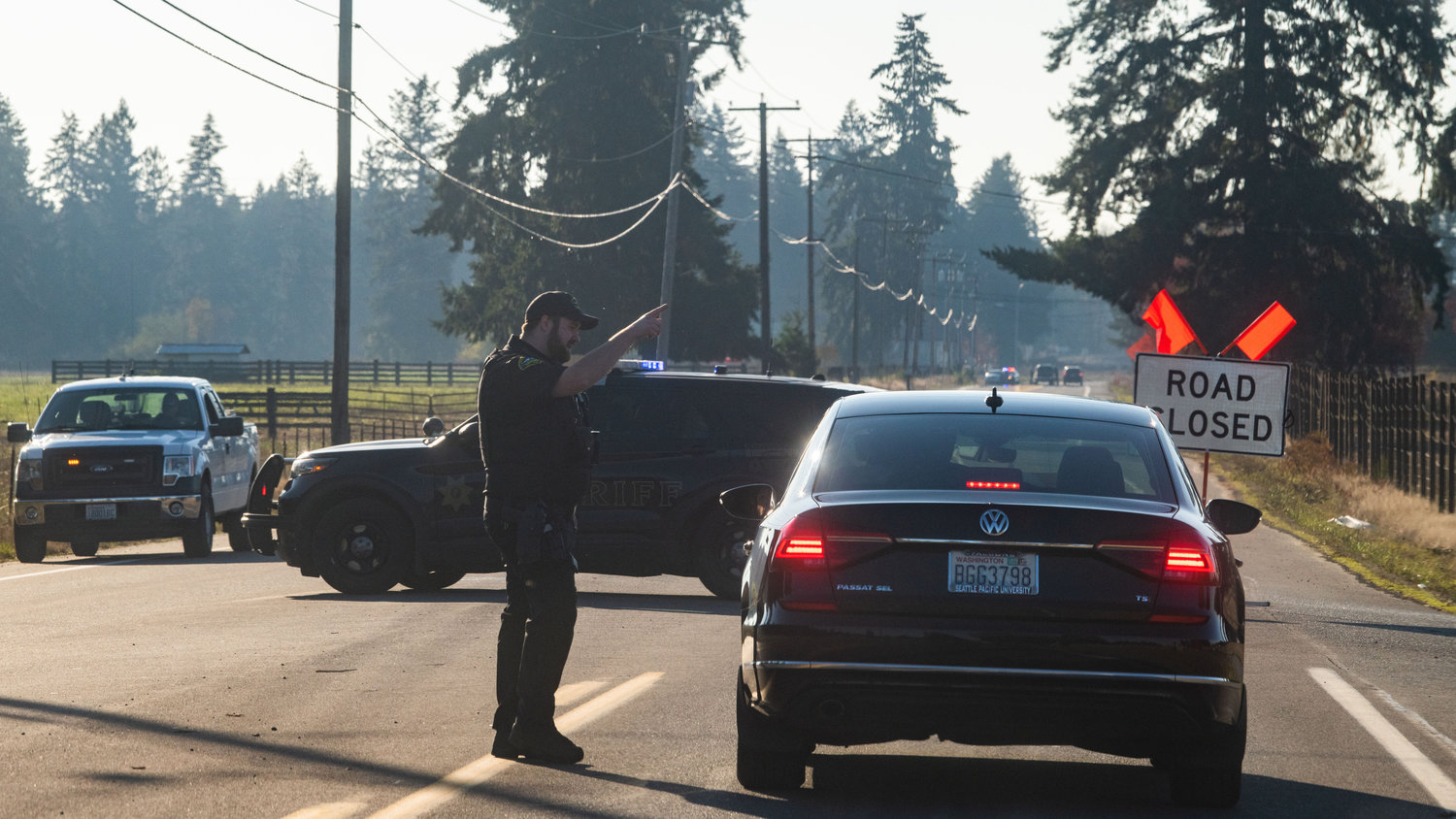 A Thurston County Sheriff Deputy gives directions to drivers navigating road closures on Monday while law enforcement investigates the scene of an officer involved shooting along Old Highway 99 SE in Tenino.