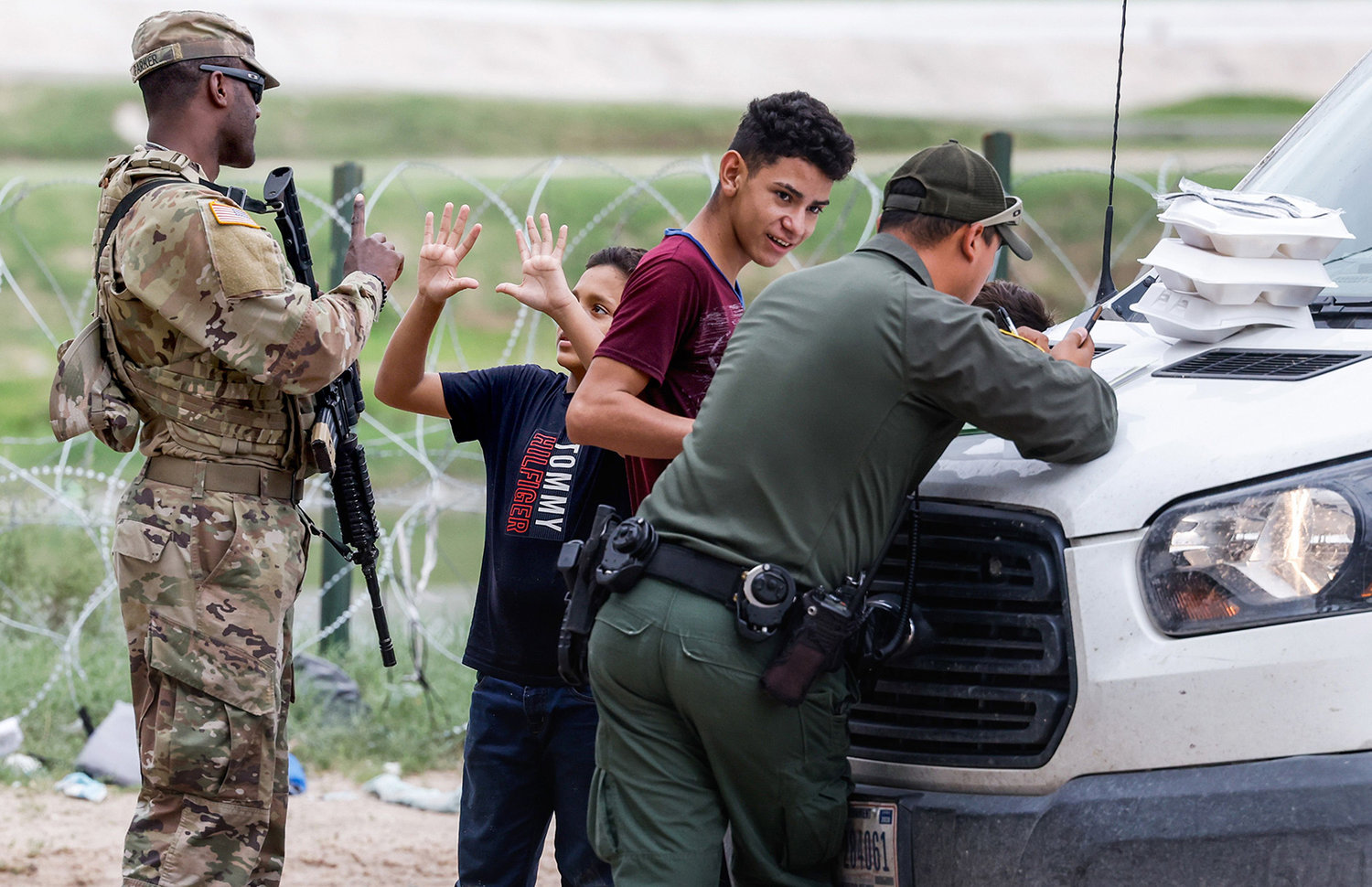 A migrant boy holds his hands up to indicate that he is 10 years old after being asked his age by a National Guard officer after he was detained crossing the Rio Grande with another child and a young boy in Eagle Pass on June 2, 2022. (Lola Gomez/Dallas Morning News/TNS)