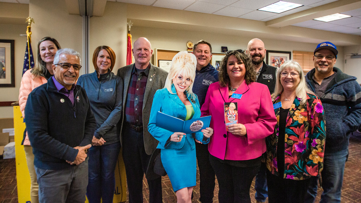 Rotarians and staff from United Way stand with a cardboard cutout of Dolly Parton to celebrate the three-year anniversary of the Dolly Parton Imagination Library being kicked off in Lewis County at the Holiday Inn in Chehalis on Friday. The program provides books for young kids at no cost to the families.