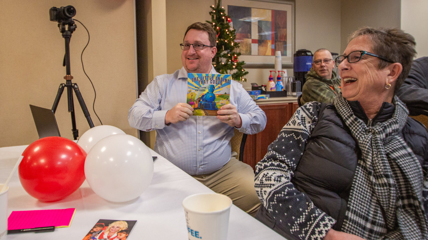 Twin Cities Rotarian Jake McGhie holds up a Dolly Parton Imagination Library children’s book he won during a drawing at the Holiday Inn in Chehalis on Friday as the club celebrated the three-year anniversary of the program’s kick-off in Lewis County.