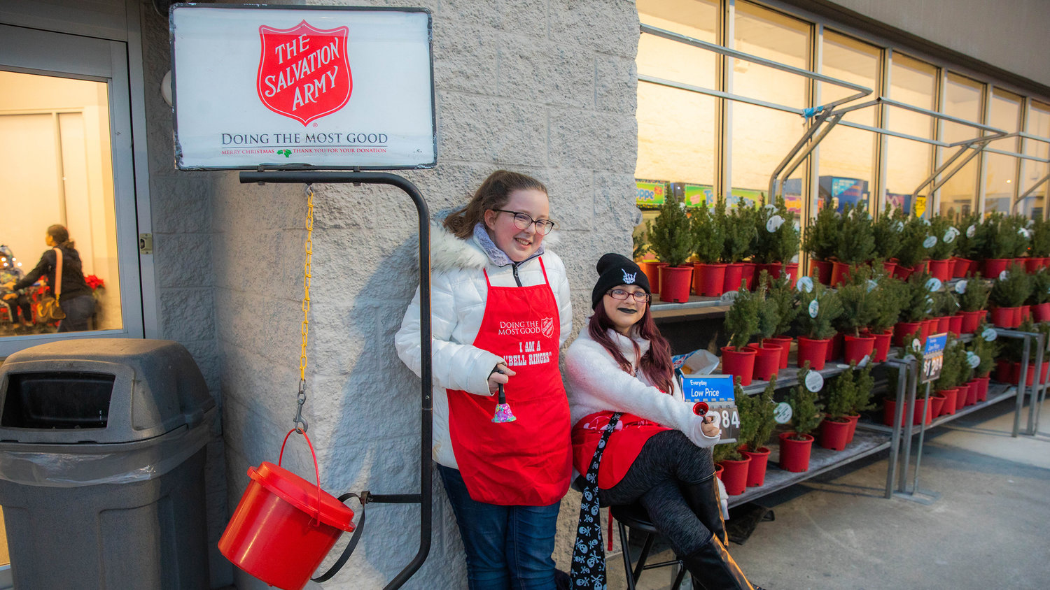 Riley Pack, 14, and Kara Martinson, 14, smile while bellringing for The Salvation Army outside Walmart in Chehalis on Monday.