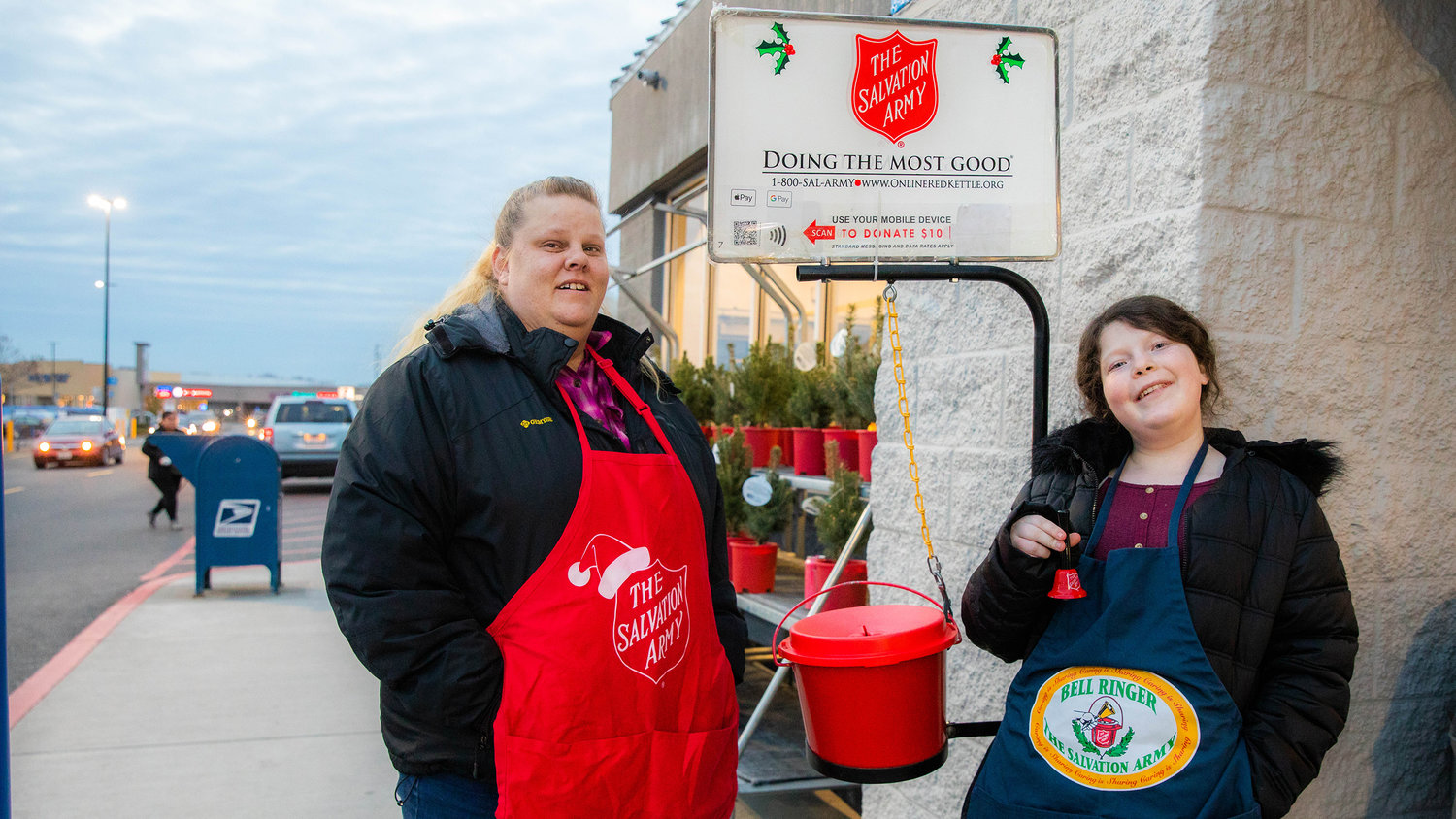 Tacy Pendleton and Elizabeth Pack, 13, pose for a photo while bellringing for The Salvation Army outside Walmart in Chehalis on Monday.