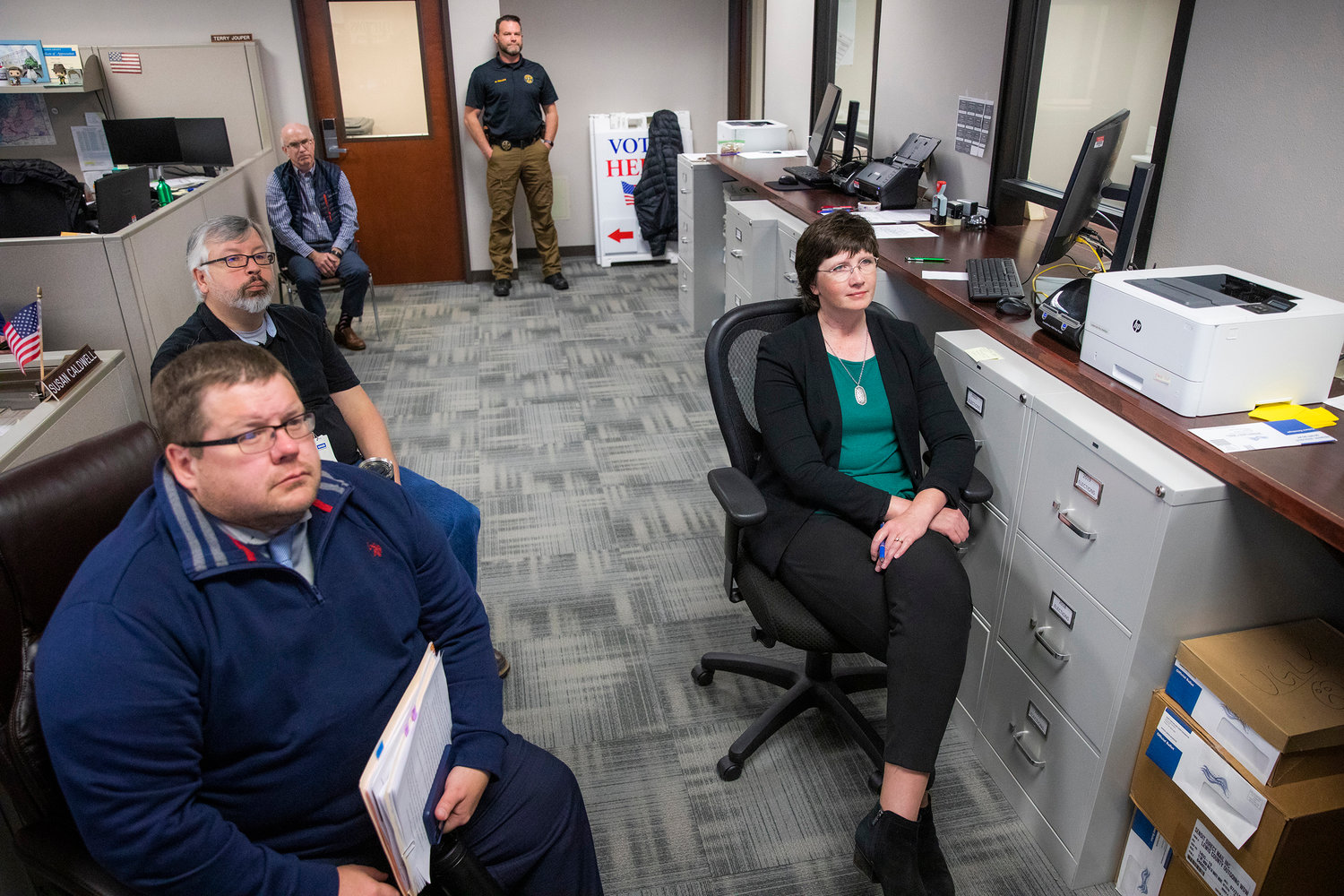 A member of the Lewis County Sheriff’s Office stands guard as Prosecutor Jonathan Meyer, Chief Deputy Auditor Tom Stanton, Auditor Larry Grove, and Commissioner Lindsey Pollock attend a Canvasing Board meeting Wednesday morning at the Lewis County Courthouse.