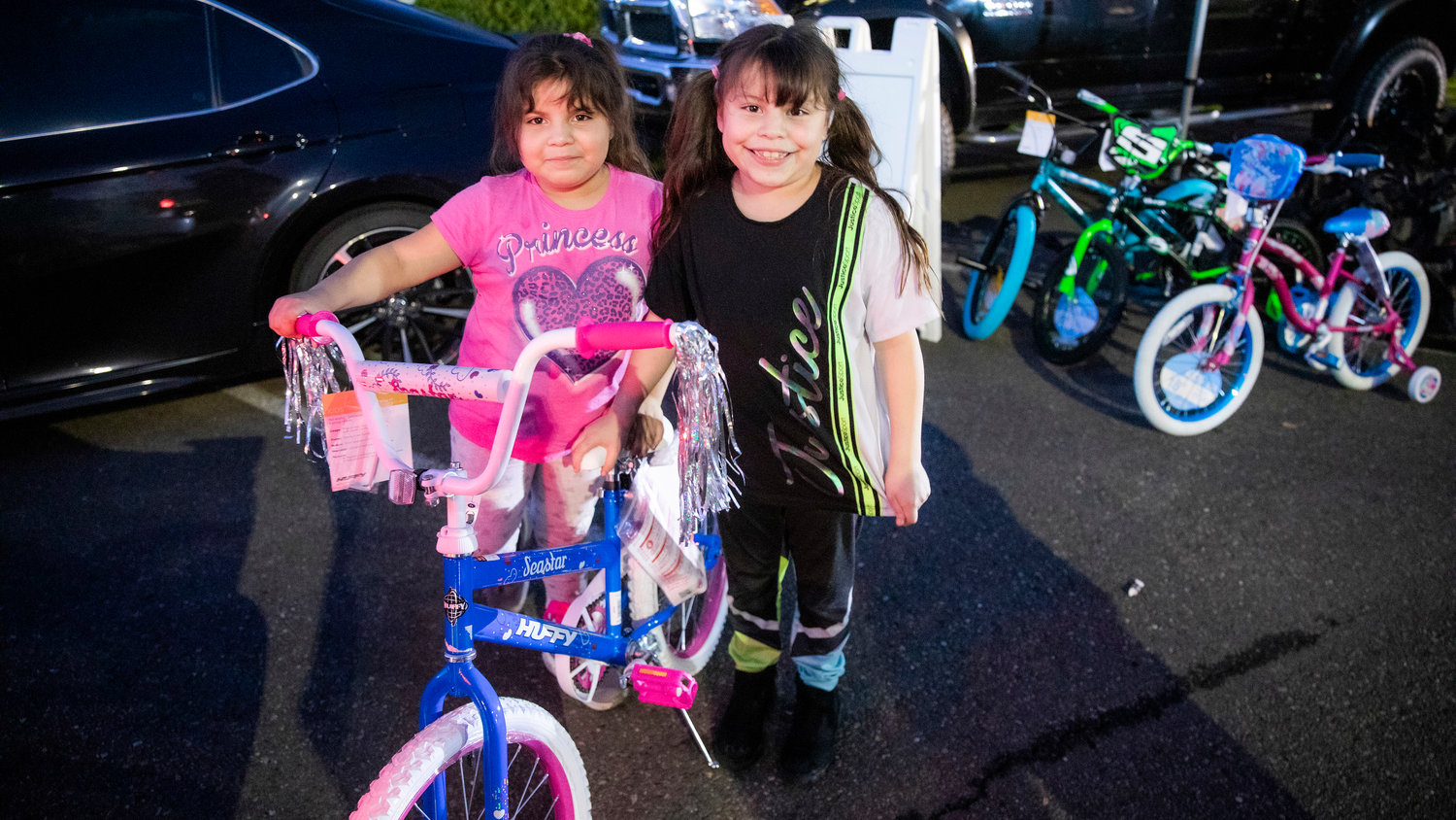 Alexa, 5, and Perla, 7, pose for a photo with their new bike during a “Choose Local Black Friday” giveaway hosted by the Centralia-Chehalis Chamber of Commerce Wednesday evening in the Lewis County Mall parking lot.