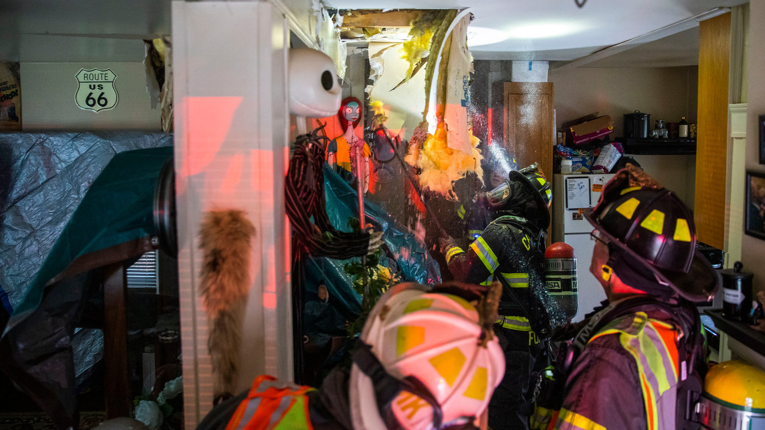 Riverside firefighters work to locate hot spots while tearing apart sections of flooring and ceiling inside a building following a residential fire in the 200 block of North Rock Street in Centralia on Friday.