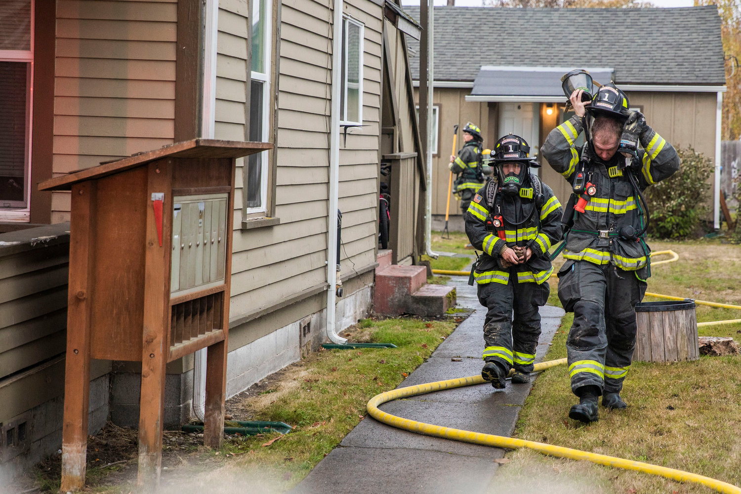 Firefighters adjust gear while responding to the scene of a residential fire in the 200 block of North Rock Street in Centralia on Friday.