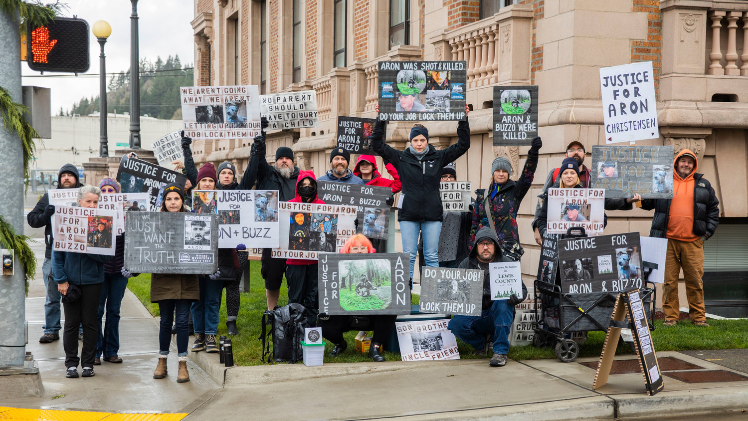 Friends of Aron Christensen pose for a photo while holding signs outside the Lewis County Courthouse while demanding justice in Chehalis on Sunday.
