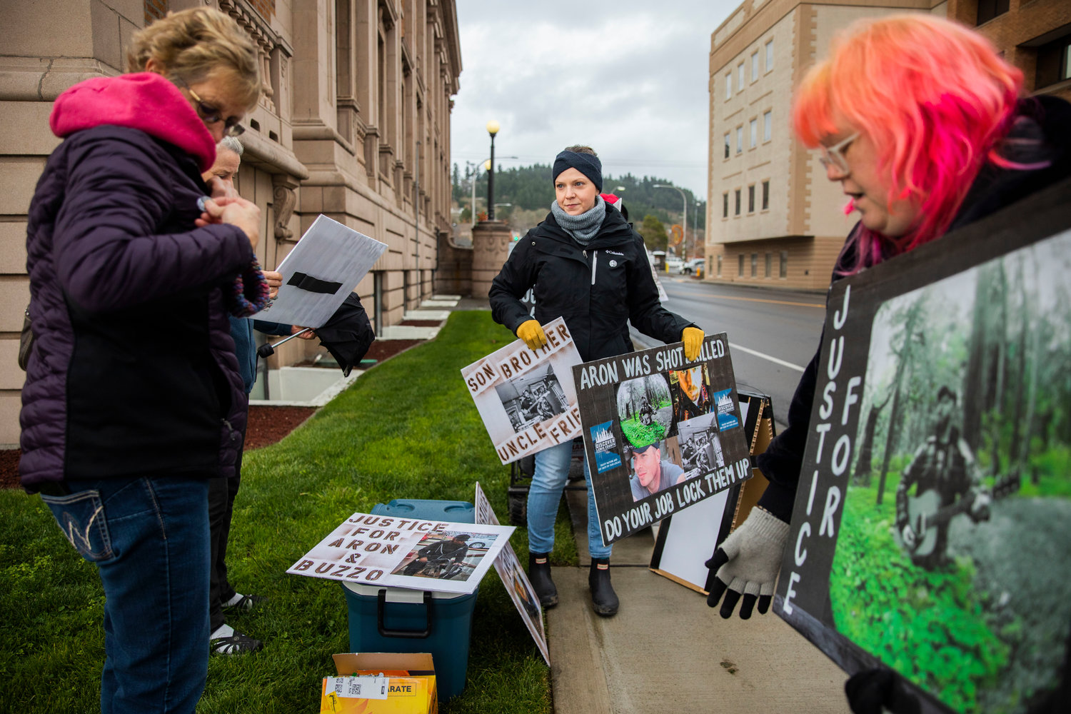 Supporters pick up signs outside the Lewis County Courthouse while demanding justice for Aron Christensen and his dog Buzzo in Chehalis on Sunday.