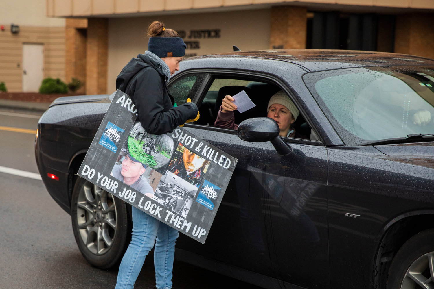 Flyers are handed to drivers outside the Lewis County Courthouse as protesters demand justice for Aron Christensen and his dog Buzzo in Chehalis on Sunday.