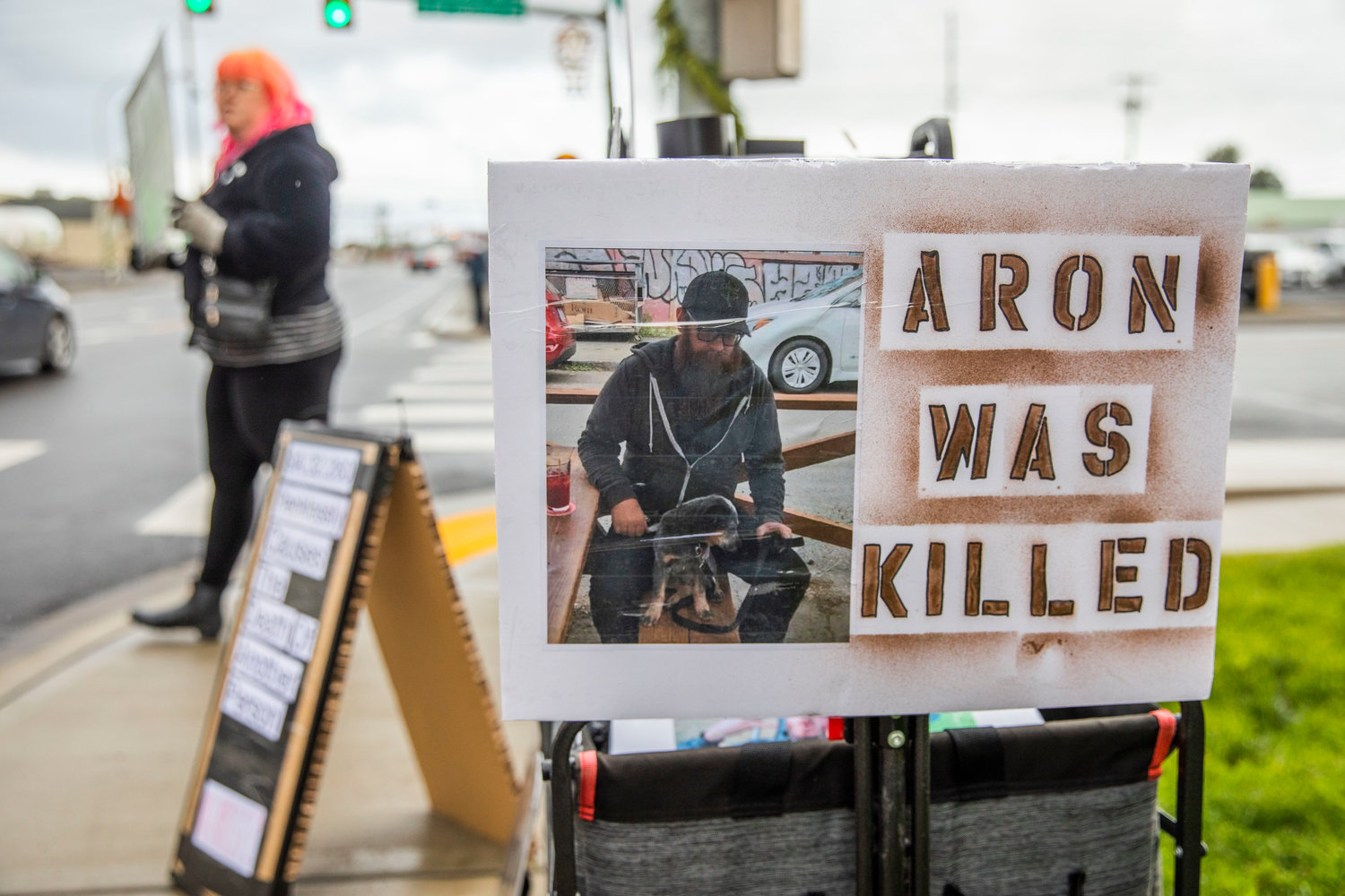 A sign features a photo of Aron Christensen with his dog Buzzo before their death along the Walupt Lake Trail outside the Lewis County Courthouse while demanding justice in Chehalis on Sunday.