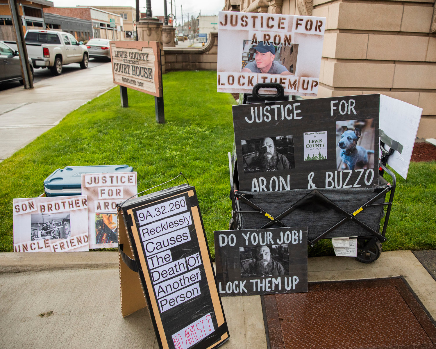 Signs sit on display outside the Lewis County Courthouse in Chehalis on Sunday as protesters demand justice for Aron Christensen and his dog Buzzo.