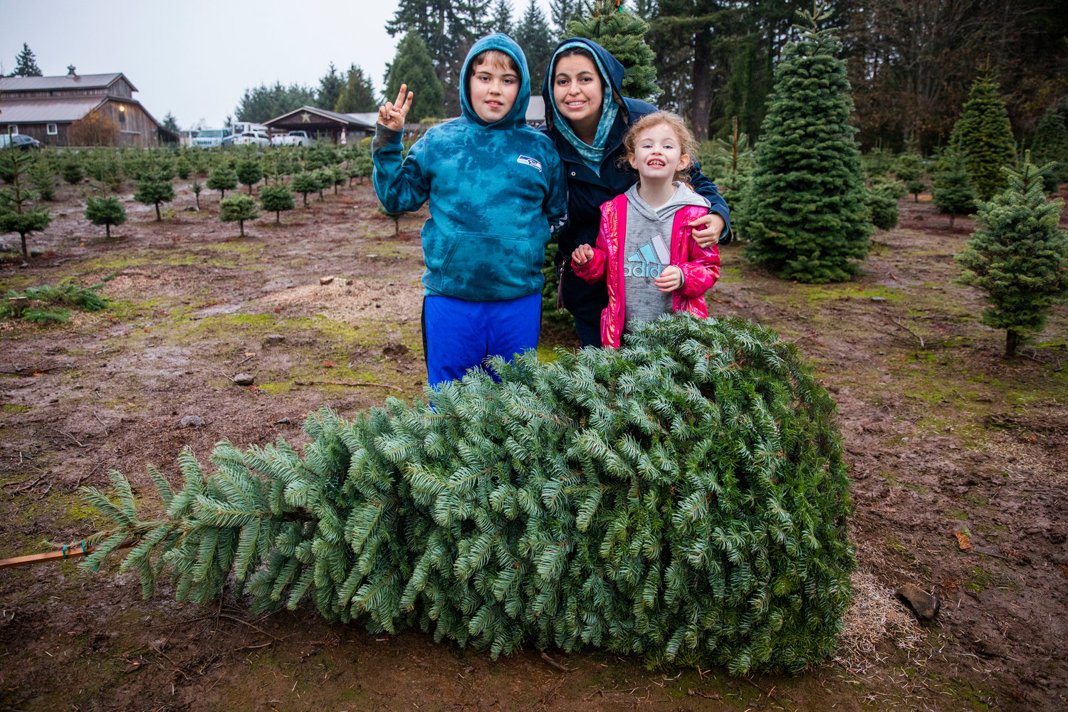 Andrea Shaw poses for a photo with Dakota, 9, and Khloe, 7, after finding a tree at the Mistletoe Tree Farm west of Chehalis on Friday.