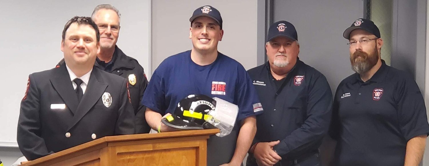 Recruit graduate Colten Whiting receiving his certificate, helmet and challenge coin. From left, firefighter Mike Goodwillie, Fire Chief Ken Cardinale, Whiting, Board Chair Colin Mason and Commissioner Greg Greene.