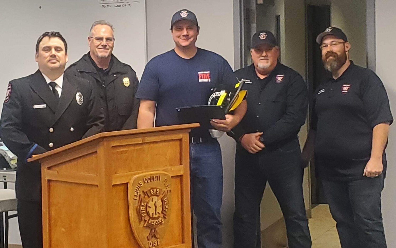Recruit Graduate Pete Harris receiving his certificate, helmet, and challenge coin. From left, firefighter Mike Goodwillie, Fire Chief Ken Cardinale, Harris, Board Chair Colin Mason and Commissioner Greg Greene.