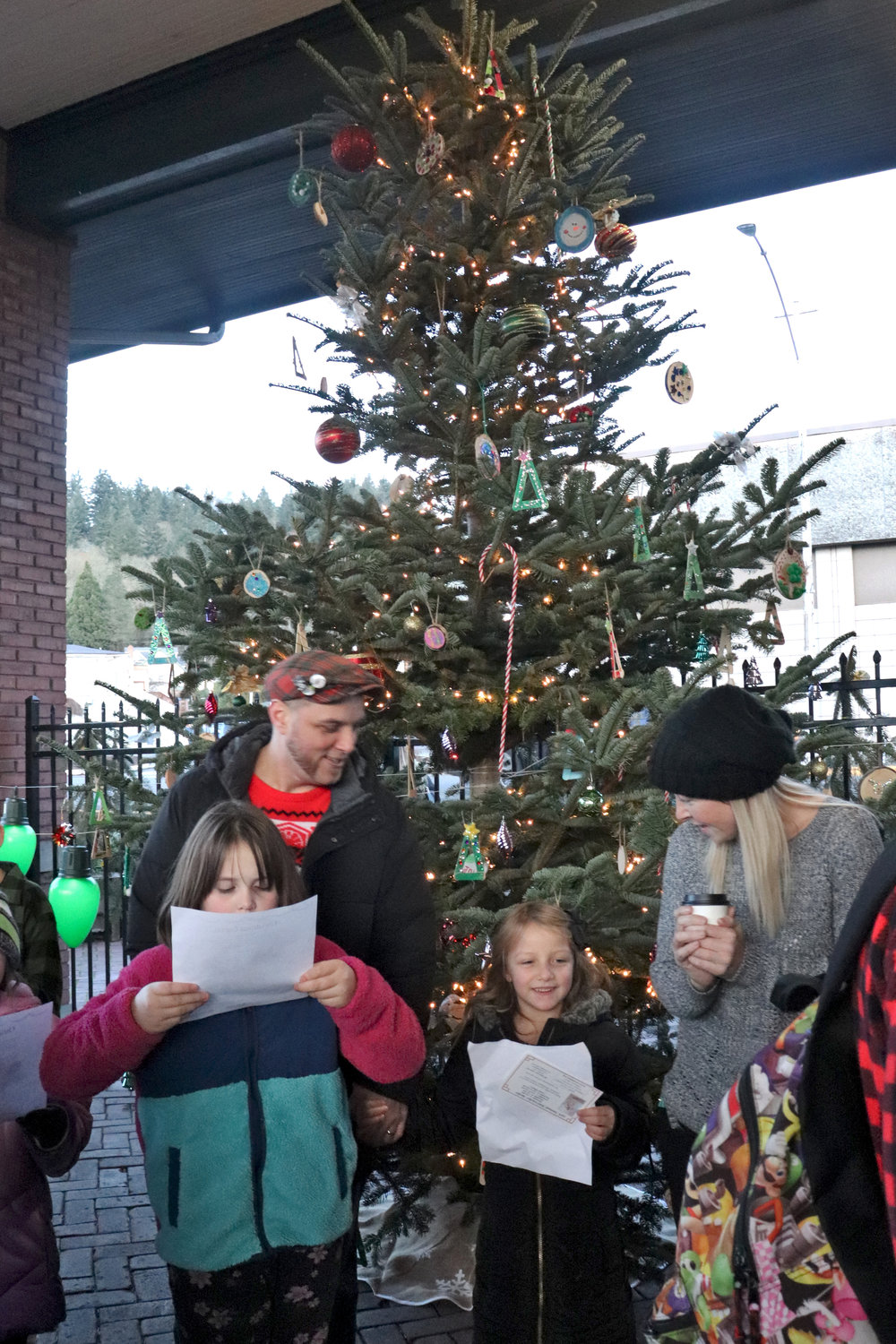 Finley-Jean Filer, center, sings carols with parents Tim Filer and Alyssa Rei during the City of Chehalis Christmas tree lighting ceremony outside the Lewis County Historical Museum on Saturday.