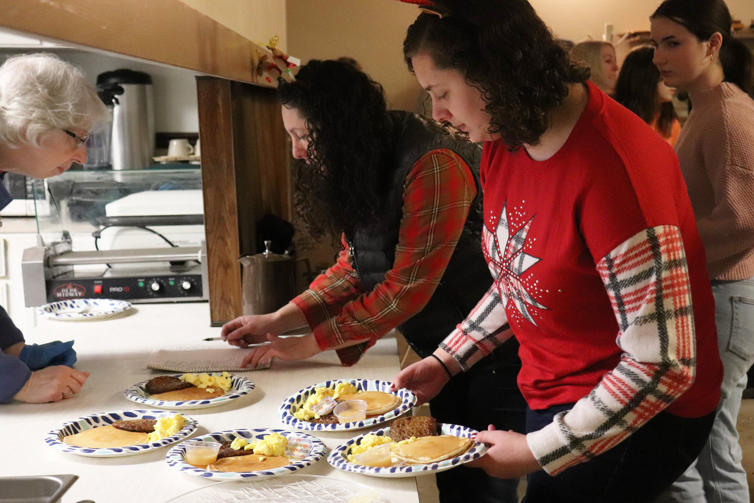 Guests collect plates of pancakes, scrambled eggs, sausage and applesauce during a Breakfast with Santa event at the Moose Family Center in Centralia on Saturday.