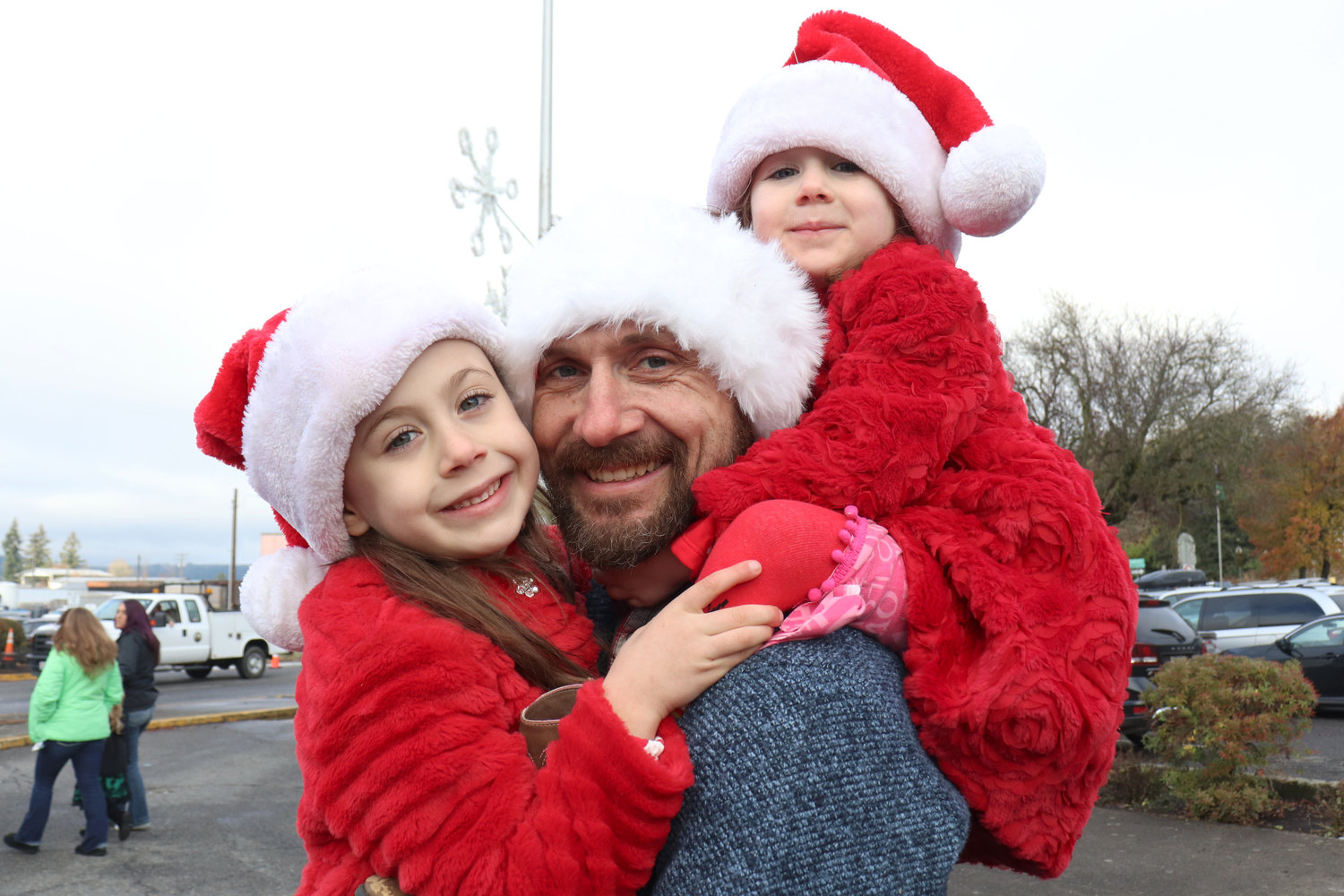 John Hornby lifts 3-year-old Anya on his shoulders and holds 6-year-old Luna to give both girls a better view of the Santa Parade in downtown Chehalis on Saturday.