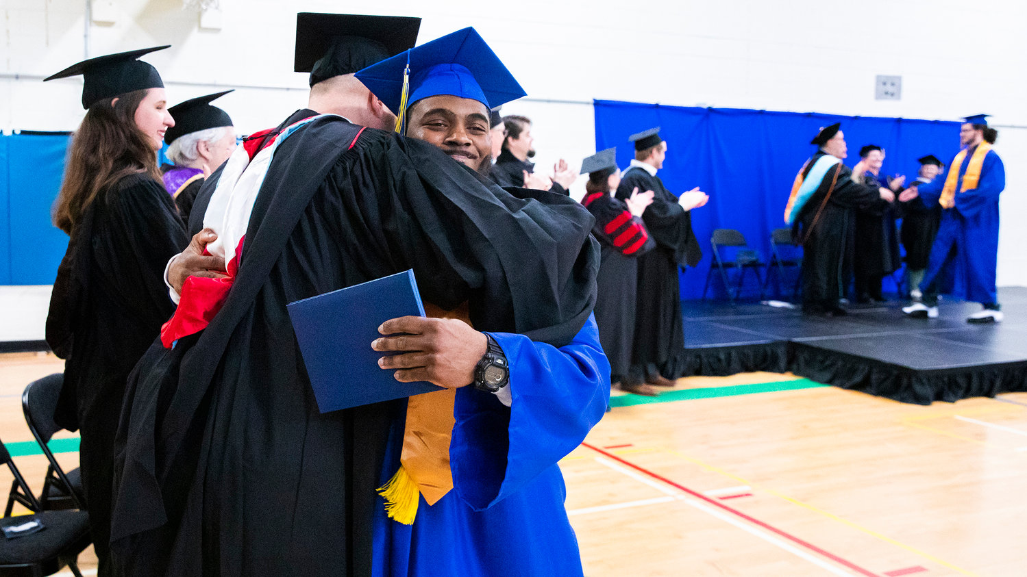 Anthony Smith smiles and receives an embrace after getting his diploma on stage during a graduation ceremony for Centralia College graduates held at the Green Hill School on Wednesday in Chehalis.
