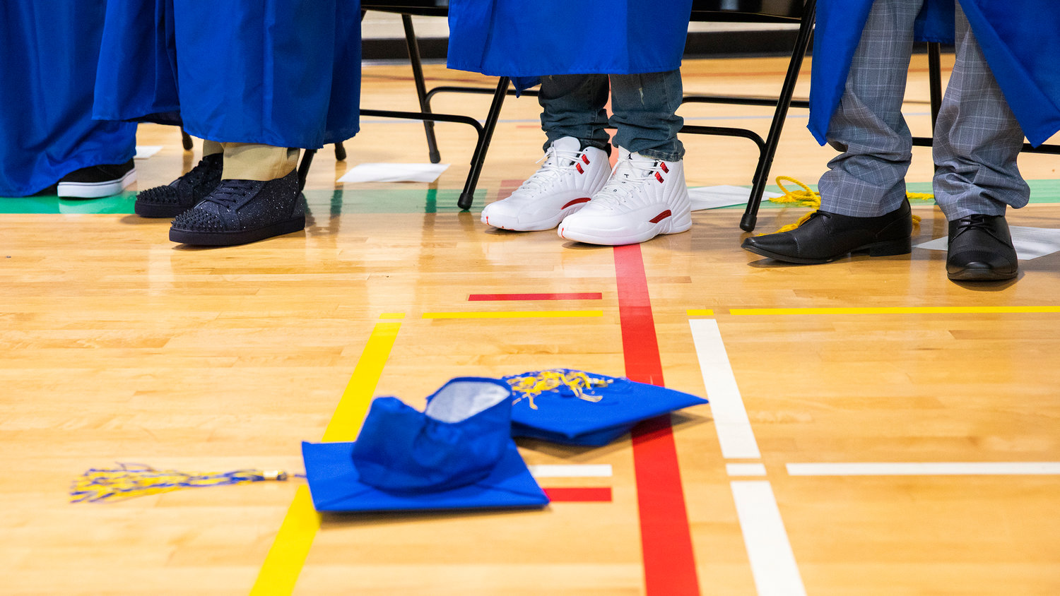 Caps and tassels rest on the floor of the gym below clean pairs of shoes during a graduation ceremony for Centralia College graduates held at the Green Hill School on Wednesday in Chehalis.