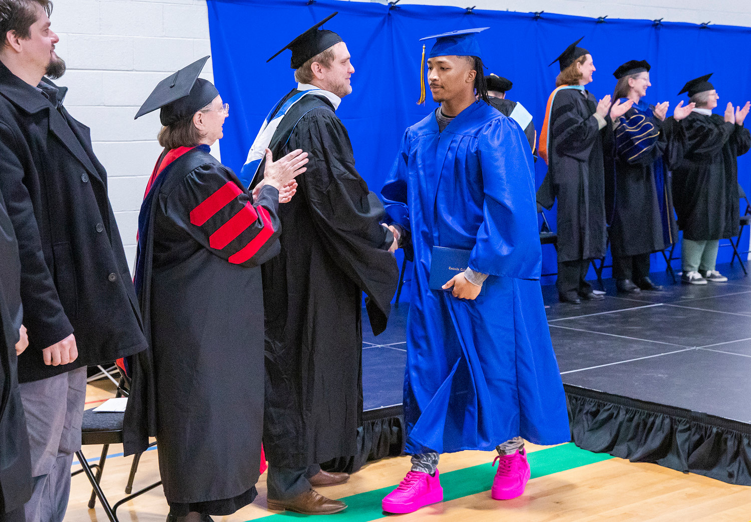 Chisten Ativalu-Ford shakes hands with Austin Majors after receiving his diploma on stage during a graduation ceremony for Centralia College graduates held at the Green Hill School on Wednesday in Chehalis.