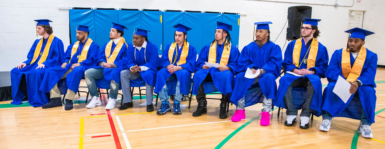 From left, Centralia College graduates Zachary Carver, Rodney Strickland, Mondrell Robertson, Lakendrick Butts, Guillermo Padilla, Edgar Calixto, Chisten Ativalu-Ford, Caya Lenay and Anthony Smith sit while sporting caps and gowns during a graduation ceremony held at the Green Hill School on Wednesday in Chehalis.