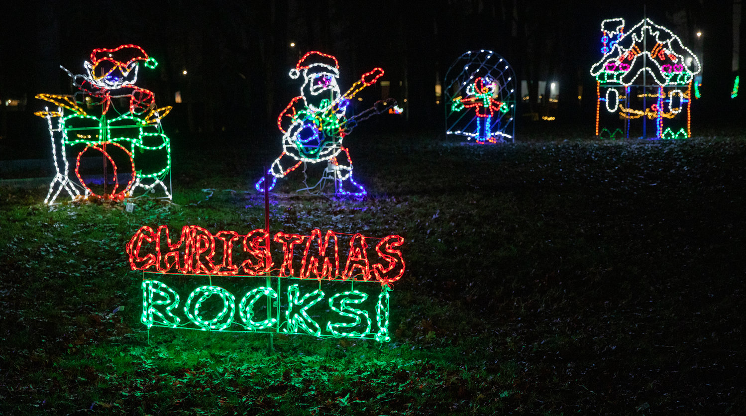 Christmas lights illuminate the words “Christmas Rocks,” in front of a guitar-playing Santa and drumming elf in Borst Park Thursday night.