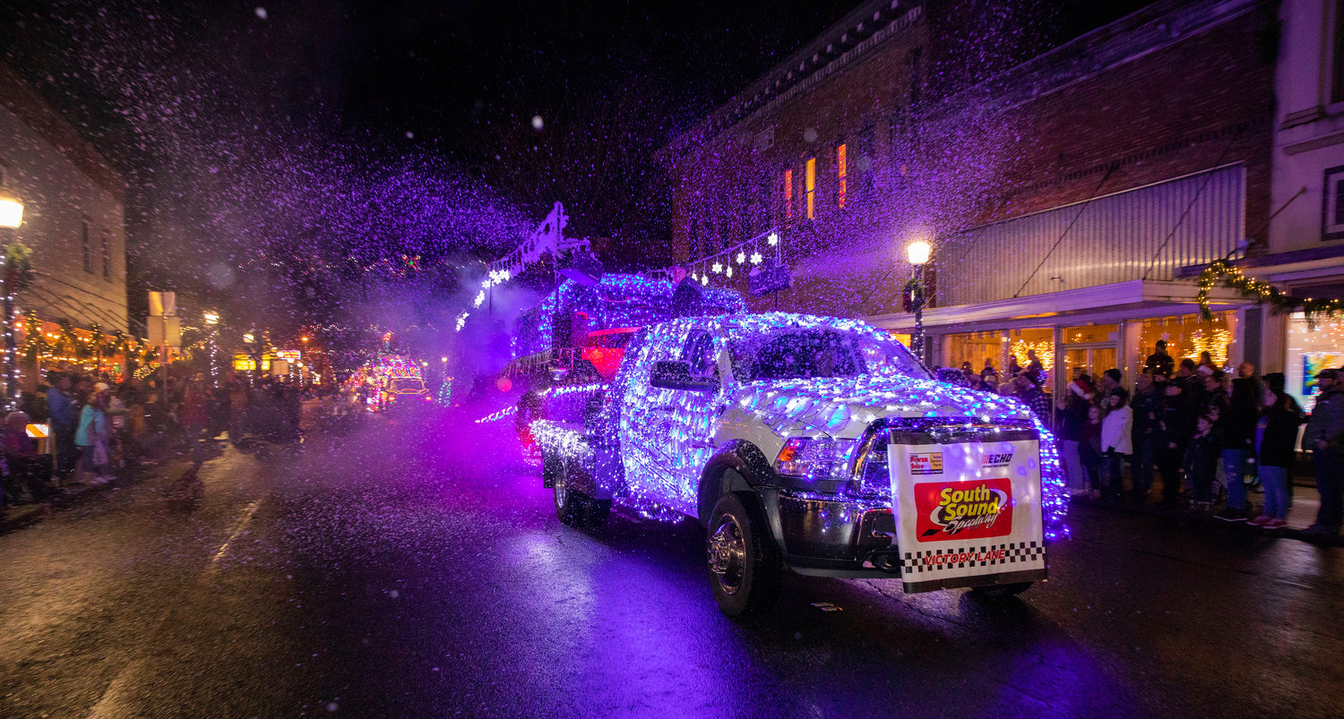 Fake snow rains down from the South Sound Speedway float during the Lighted Tractor Parade Saturday night in downtown Centralia.