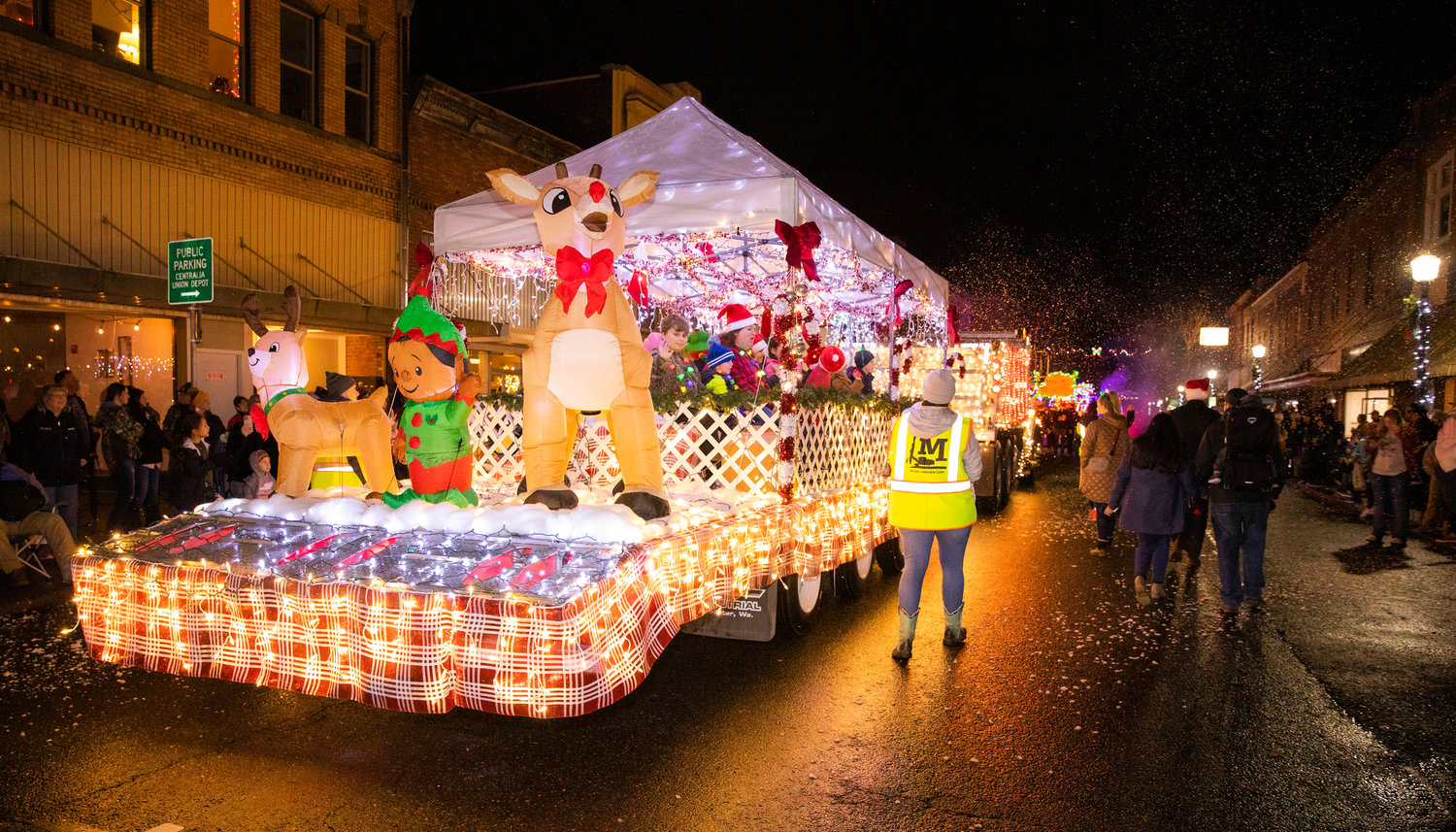 Fake snow falls as crowds gather for the Lighted Tractor Parade Saturday night in downtown Centralia.