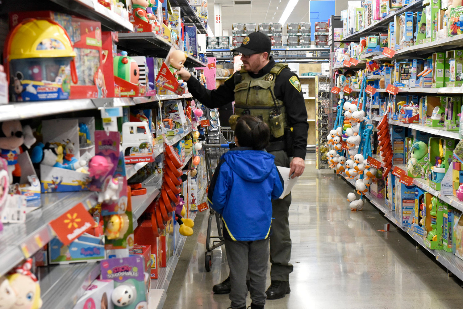 A Lewis County Sheriff’s Office deputy helps a kid pick out a toy at Chehalis Walmart during the Shop With a Cop event on Wednesday.