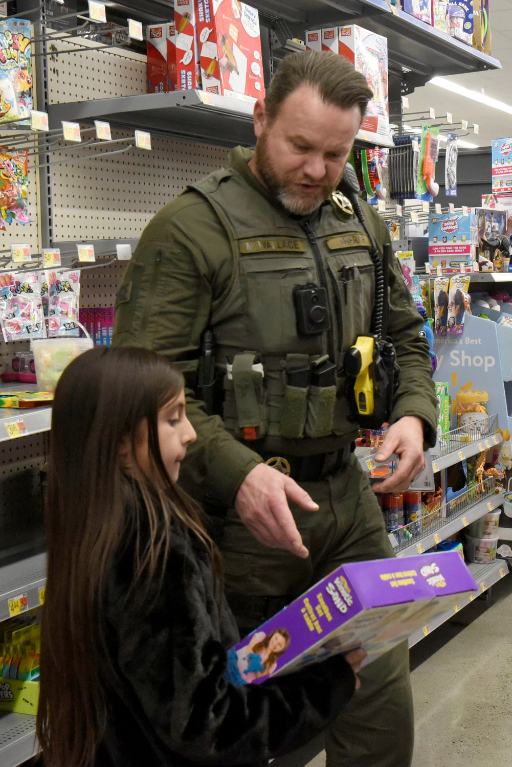 A Lewis County Sheriff’s Office deputy helps a kid pick out a toy at Chehalis Walmart during the Shop With a Cop event on Wednesday.