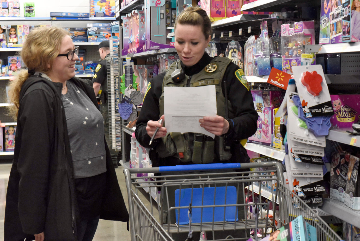 A Lewis County Sheriff’s Office deputy goes over a kid’s Christmas list during the Shop With a Cop event at Chehalis Walmart on Wednesday.