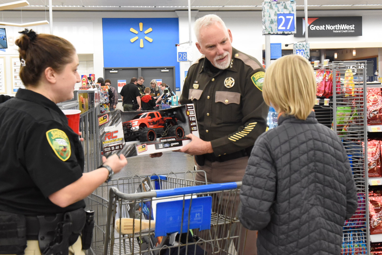 Lewis County Sheriff Rob Snaza admires the gifts a Shop With a Cop participant picked out at Chehalis Walmart on Wednesday.