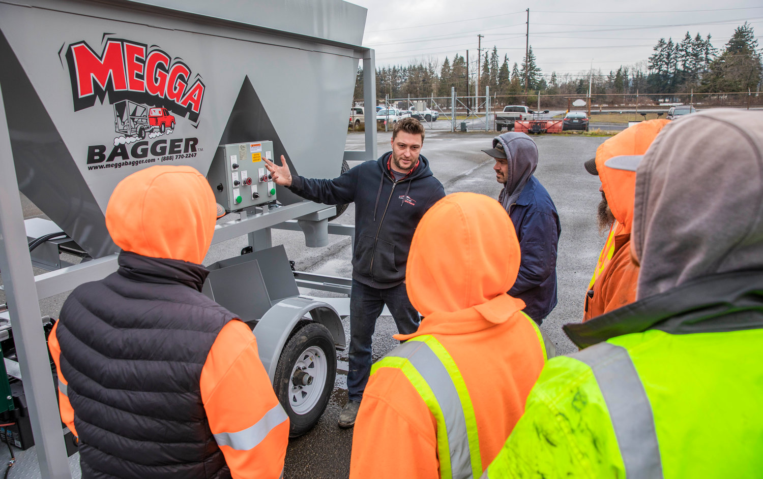 Morris Malone, co-owner of The Bag Lady INC, a Puyallup-based company that creates sandbag machines, demonstrates operation of the machine to Centralia Public Works staff Monday at the department’s shop on Reynolds Avenue.