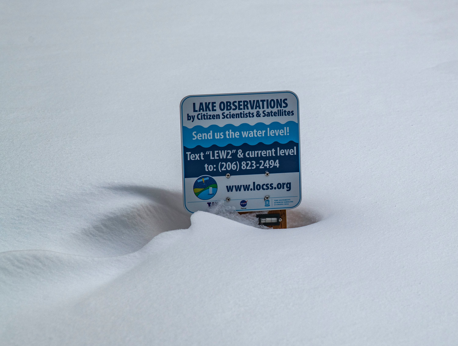 A sign on frozen Leech Lake is nearly covered in snow near the border of Yakima and Lewis counties at the White Pass Ski Area’s Nordic trails on Sunday.
