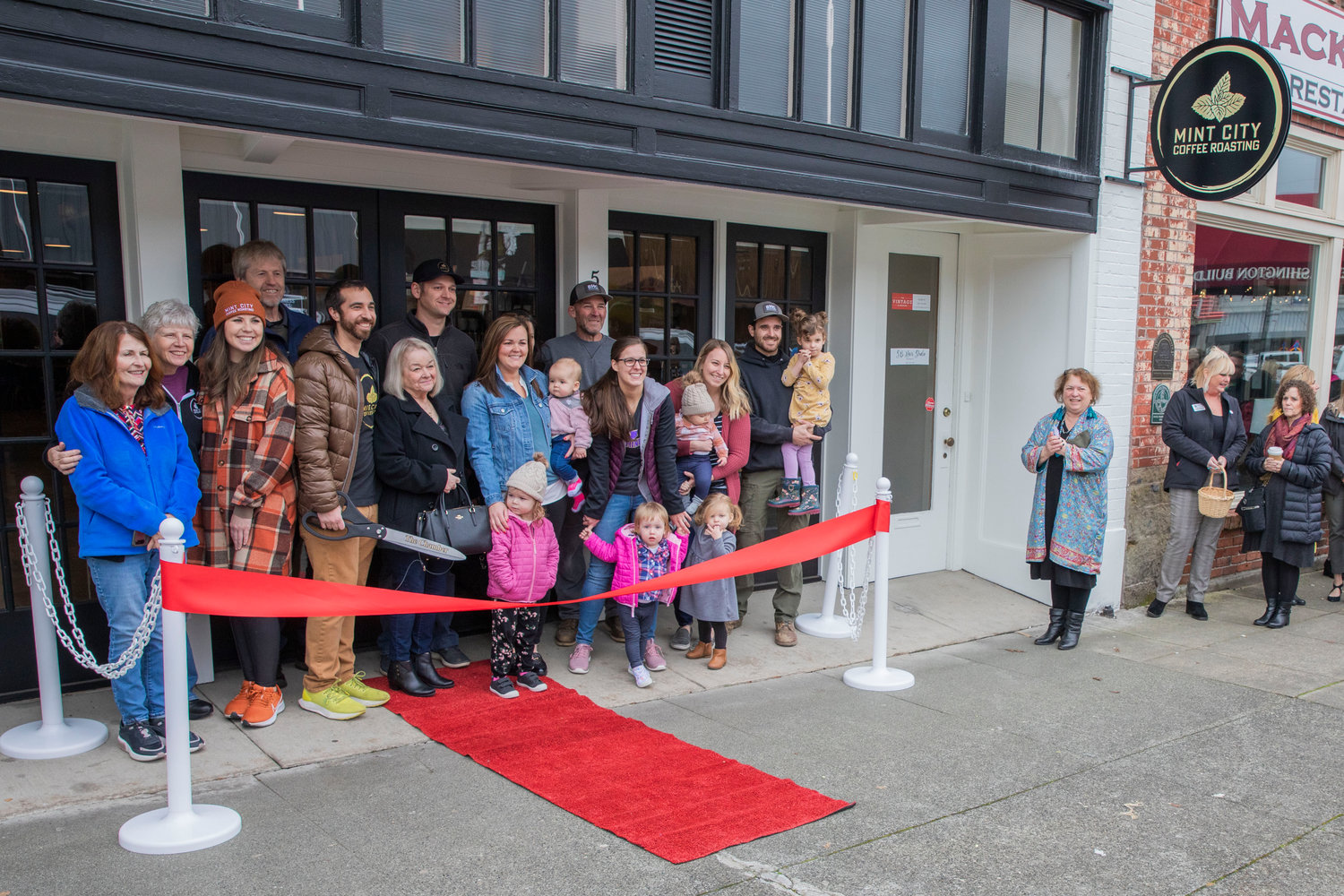 Family members of Sarah and Kyle Askin and Jason and Shawna Boettner join in for a photo outside Mint City Coffee during a ribbon-cutting ceremony in Chehalis on Tuesday.
