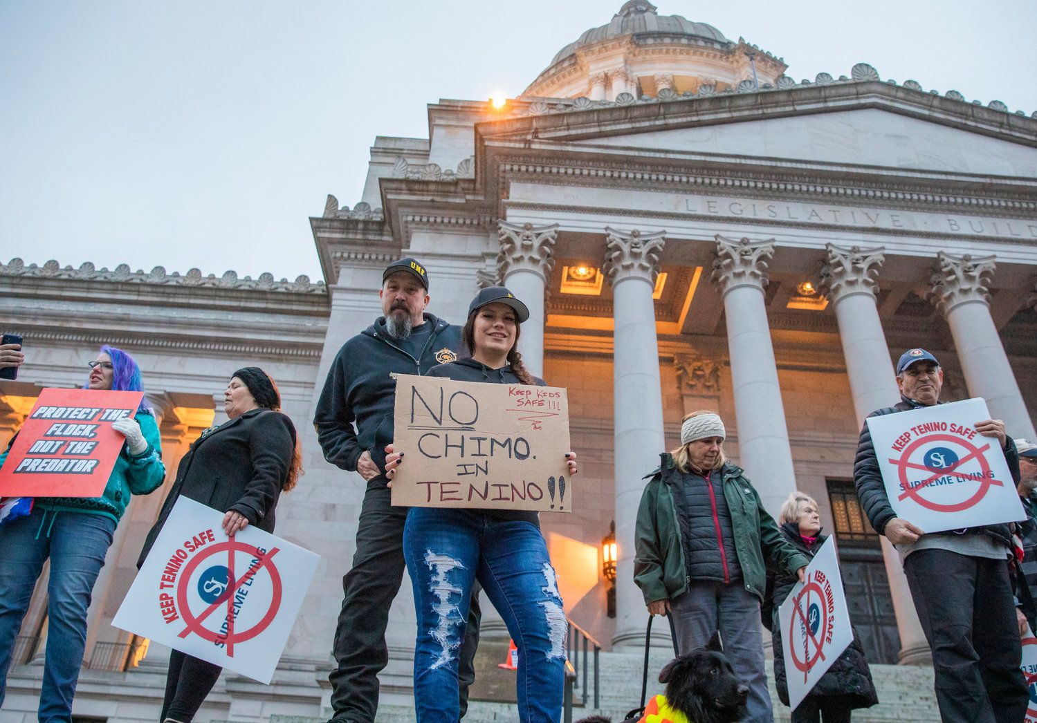 Tenino area residents gather outside the Washington State Capitol building in Olympia while holding signs and protesting Supreme Living in late January.