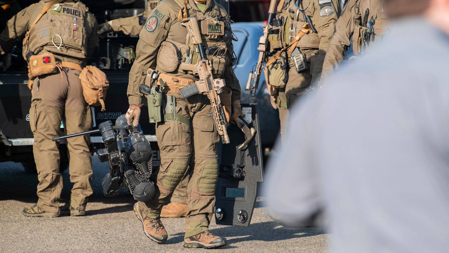 SWAT members carry shields, weapons and robots through an active scene in the 1300 block of Windsor Avenue in Centralia on Thursday.